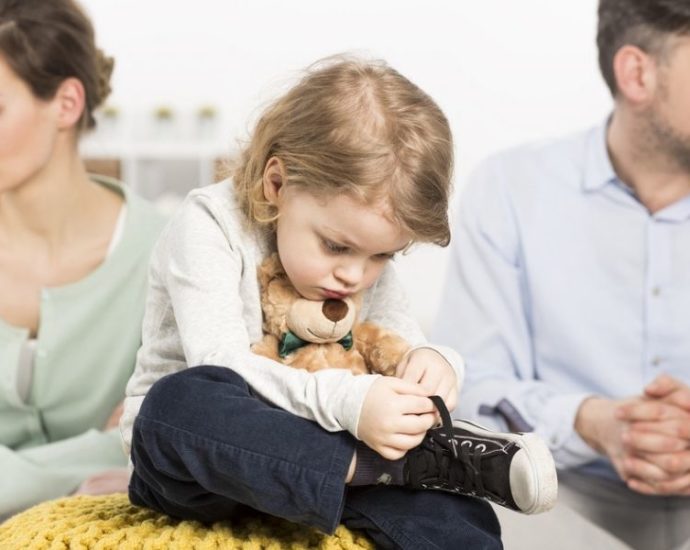 gloomy young family with a sad little boy hugging a teddy bear, and his parents with depressed looks