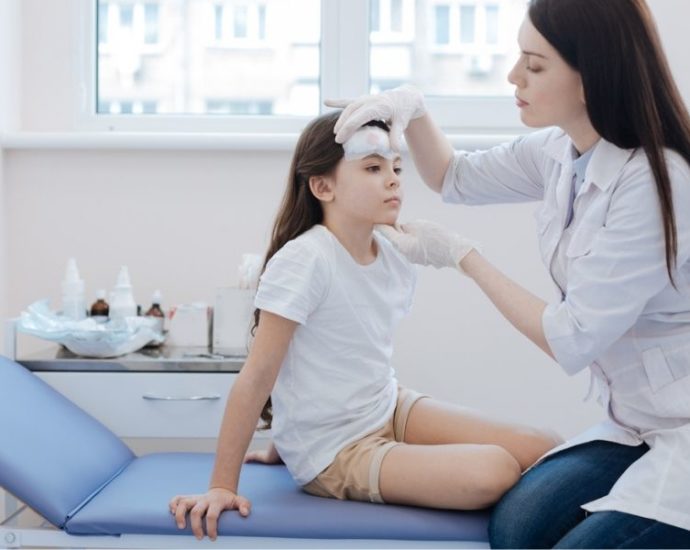 doctor examining girl's forehead