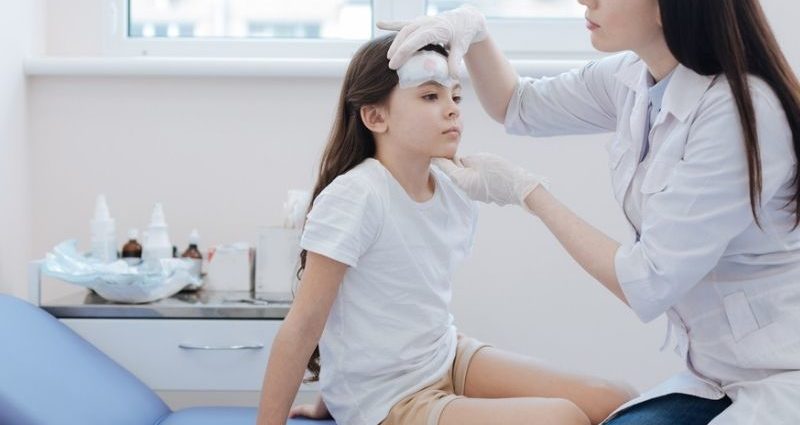 doctor examining girl's forehead